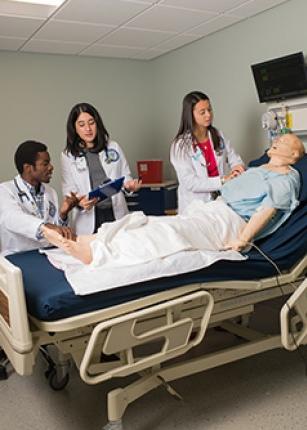 健康 graduate 学生 practicing on a dummy in the Simulation Lab